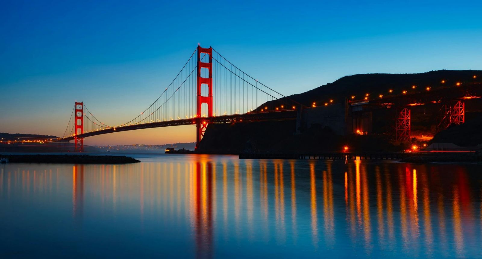 Suspension bridge at night with traffic light trails