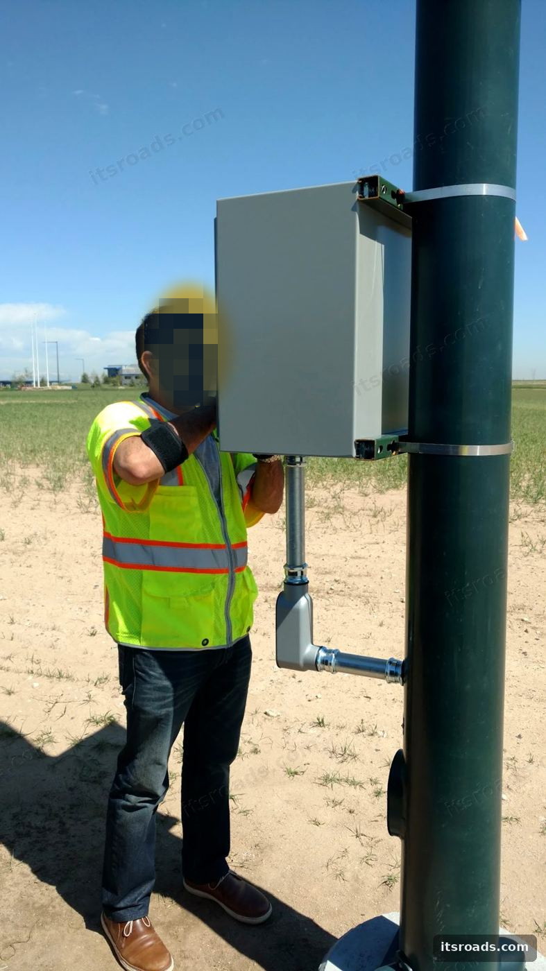 Technician mounting a NEMA enclosure on a steel pole